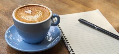 Coffee cup, notebook and pen